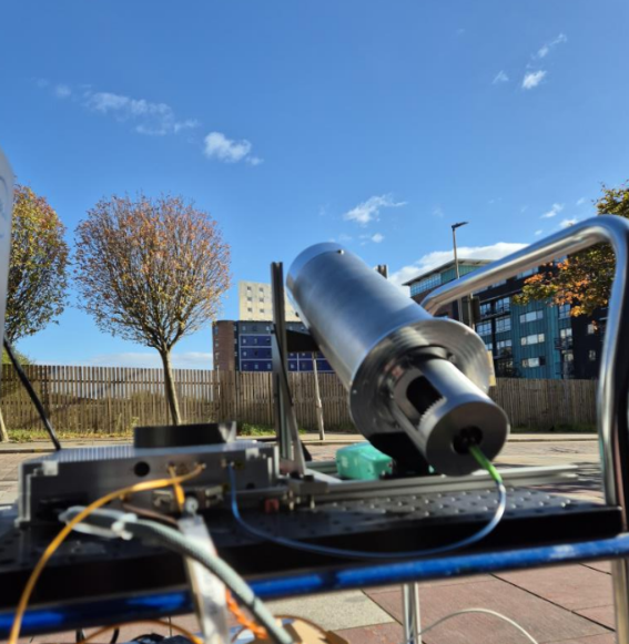 Lidar equipment and a telescope mounted on a trolley in a paved area. The telescope is pointed at the sky.